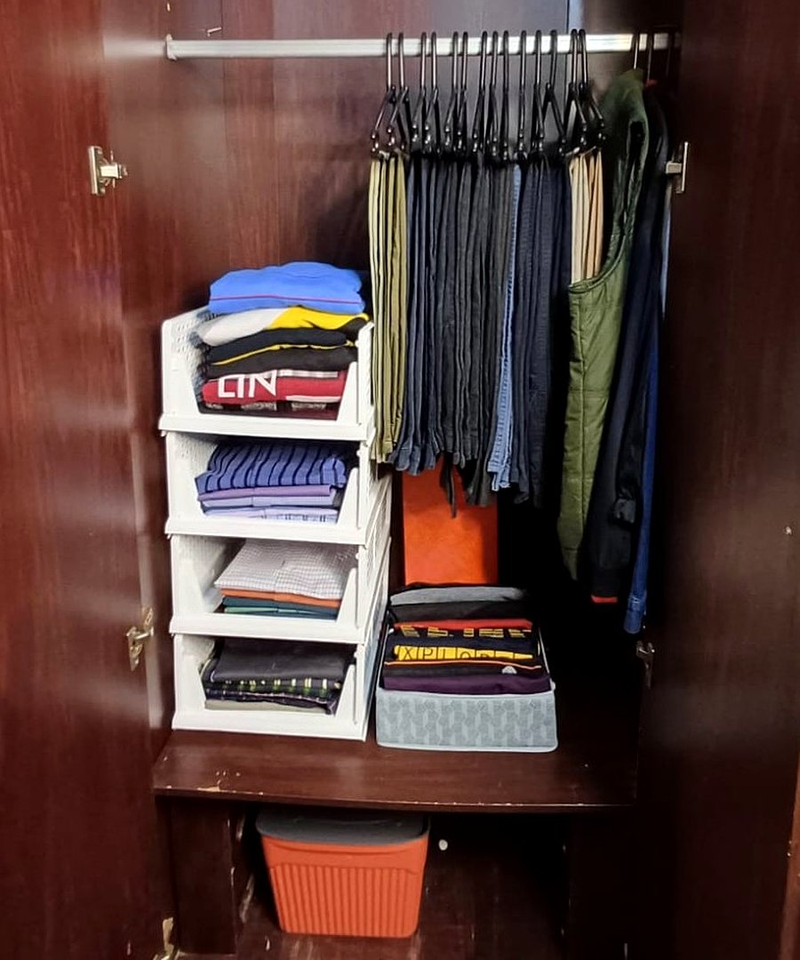Men's formal wardrobe after professional organizing — color-sequenced hangers, vertical stacking shelves added, file-folded clothes, dedicated storage bin